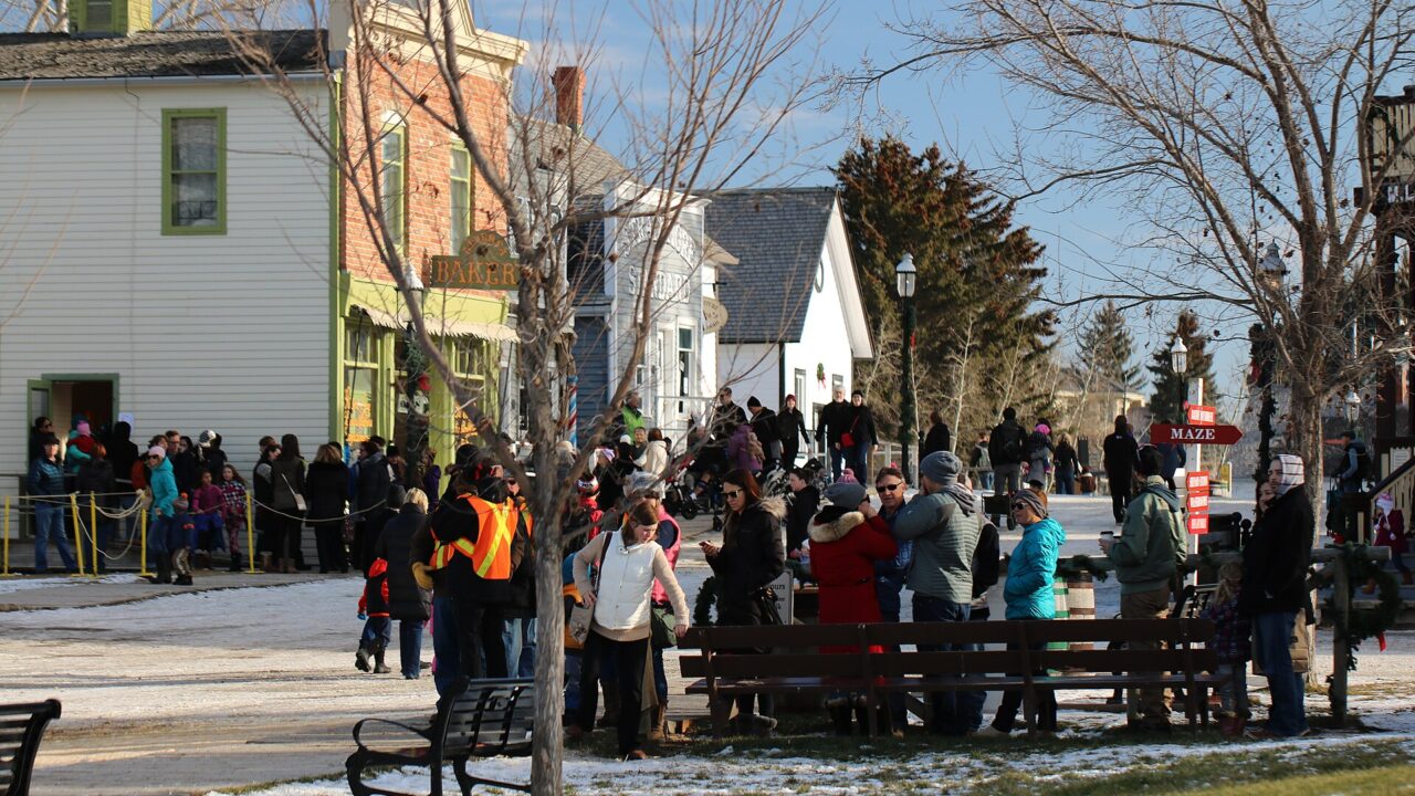 Visitors in winter coats lining up outside historic buildings at Heritage Park's Once Upon a Christmas event in Calgary, November 2015.