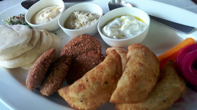 A mezze platter with falafel, hummus, tzatziki, baba ganoush and pita; an illustration, not taken at Kama.