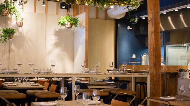 The set tables, hanging plants and open kitchen inside Ten Foot Henry restaurant in Calgary, photographed in June 2016.
