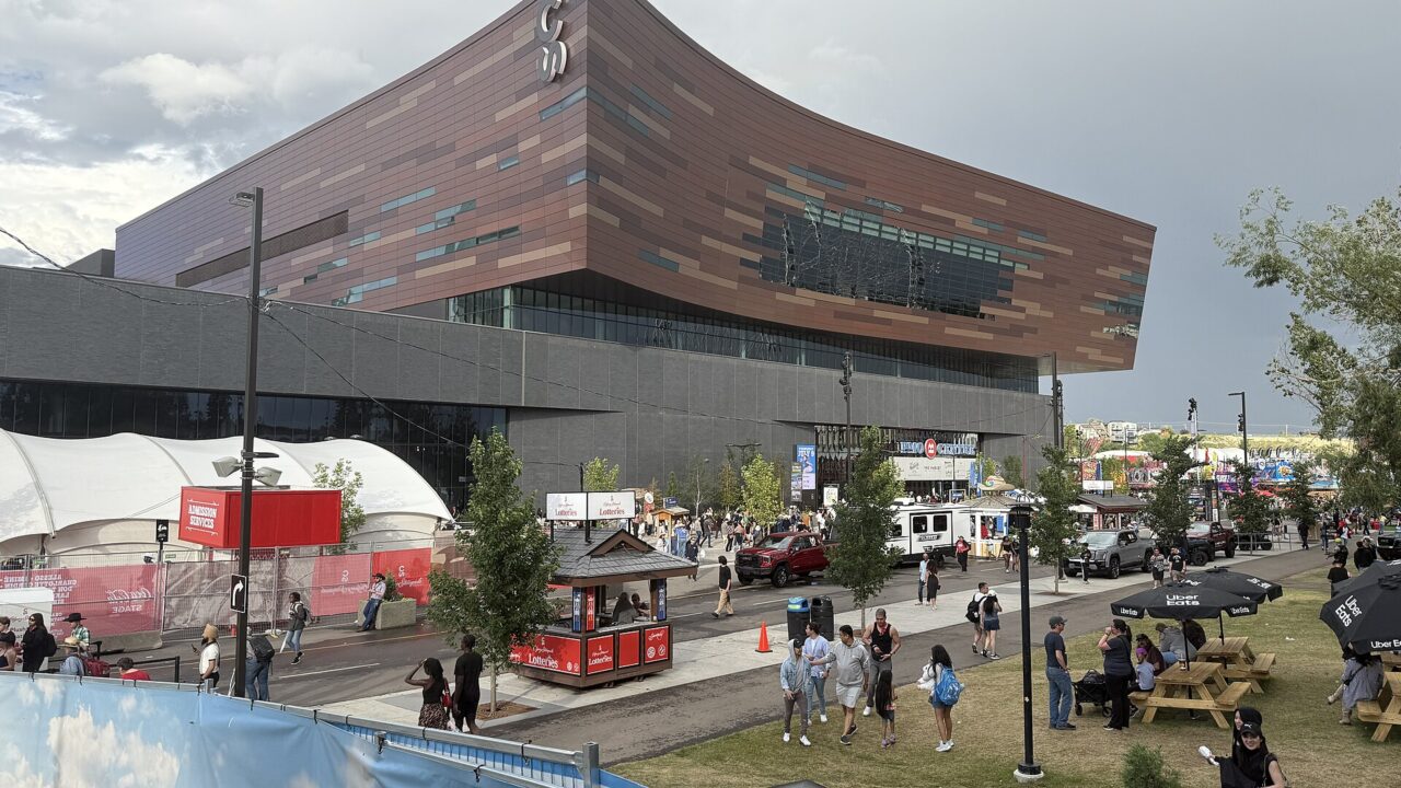 Visitors on the Stampede Park grounds beside the copper-clad BMO Centre during the Calgary Stampede in July 2025.